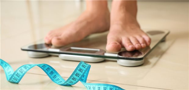 Zwei Füße auf einer Waage mit Maßband.