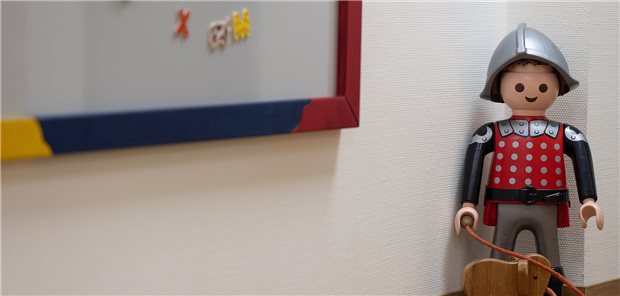 Eine Playmobilfigur steht im Flur einer Kinderarztpraxis.