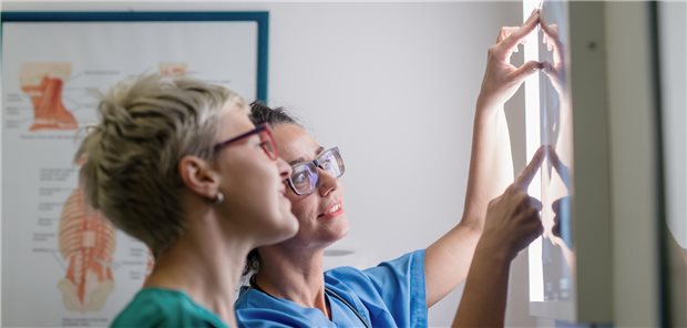 Zwei Ärztinnen beraten über das Röntgenbild eines Patienten mit Verdacht auf einen Knochenbruch.