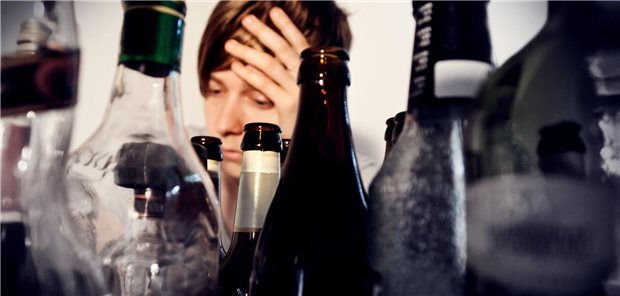 Eine Frau sitzt hinter vielen leeren Flaschen