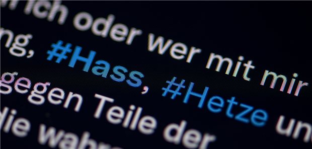 Auf dem Bildschirm eines Smartphones sieht man die Hashtags Hass und Hetze in einem Twitter-Post.