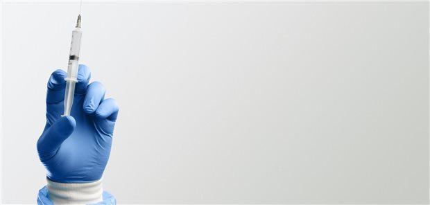 Ein Arzt hat einen Spritze mit onkolytischen Viren zur Anwendung in Form einer intratumoralen Injektion in der Hand.