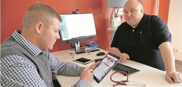 Ärzte und AOK holen dezentrale EPA nach Deutschland Hausarzt Dr. Christian Bauer (r.) im Gespräch mit einem Patienten, der sich über die AOK-EPA informiert.