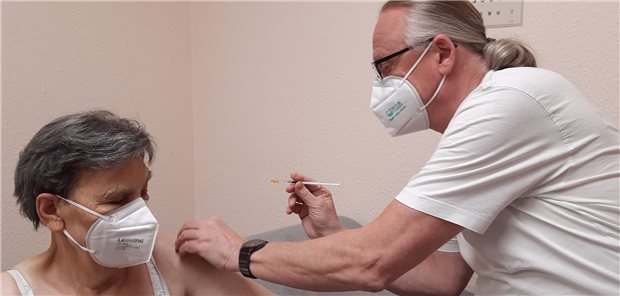 Hausarzt Holger Fischer impft eine Patientin gegen COVID-19.