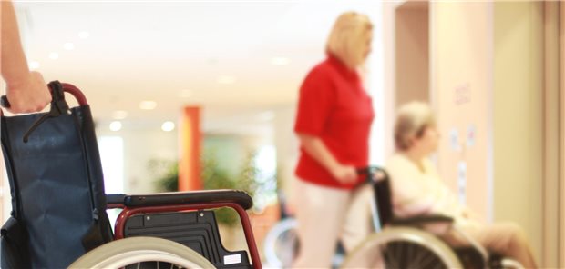 Frau schiebt eine Person im Rollstuhl