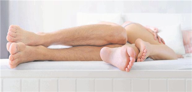 Ein junger Mann und eine junge Frau liegen zusammen im Bett. Zu sehen sind nur die Füße und Beine der Personen. 