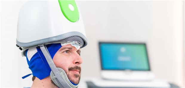 Hier wird der Helm vorgeführt, der für die repetitive, transkranielle Magnetstimulation verwendet wird. 