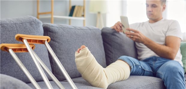 Mann auf der Couch mit Gipsverband um Unterschenkel