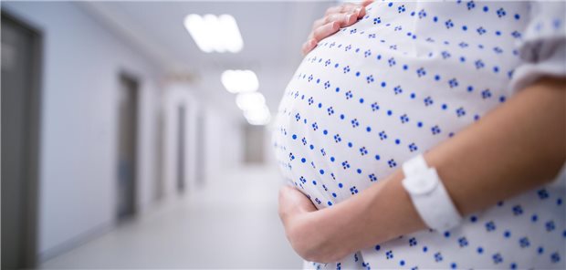 Eine schwangere Frau hält sich den Bauch.