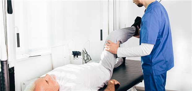 Arzt untersucht Mann auf Liege.