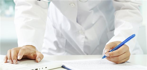 Ein Arzt am Tablett hält einen Stift in der Hand-