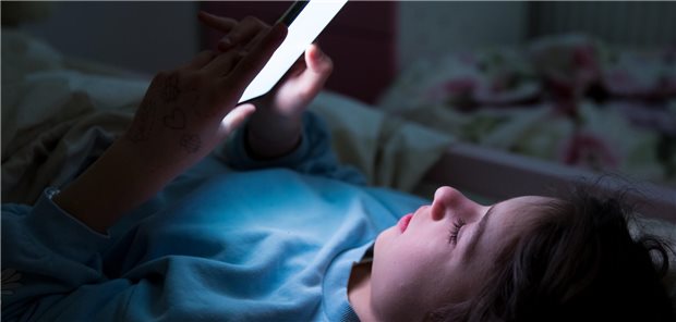 Schlafqualität von Jugendlichen: Bildschirm vor dem Schlafengehen ok, im Bett nicht Mädchen liegt im Bett und spielt am Smartphone