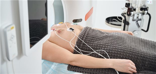 Screening mittels Koronar-CT: Was das bringen könnte Ein junger Mann liegt im Herz-CT und bekommt gleichzeitig ein EGK geschrieben.