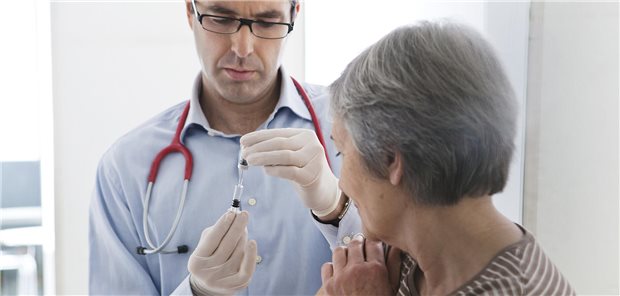 Arzt hält neben Patientin Spritze senkrecht