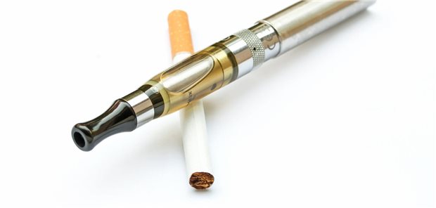Eine E-Zigarette liegt angelehnt an eine herkömmliche Zigarette.