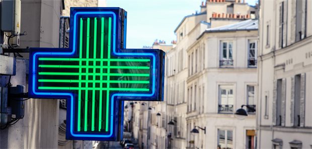 grünes Apotheken-Kreuz an Hausfassade in Frankreich
