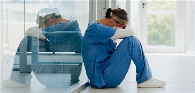 Eine Klinikangestellte sitzt weinend auf dem Boden.