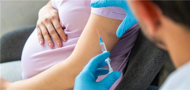 Arzt mi Spritze vor Frau mit Babybauch