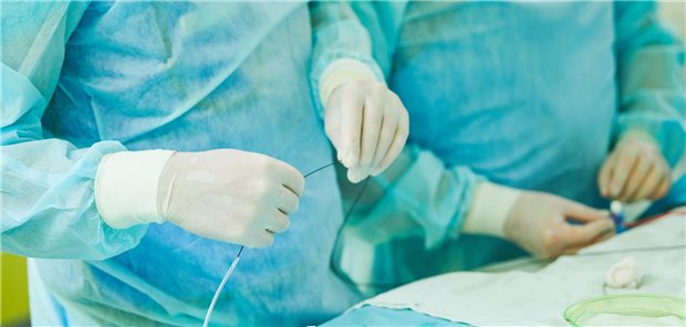 Chirurg führt eine perkutane Koronarintervention bei einem Patienten mit chronischen Koronarsyndrom durch um dessen Krankheitssymptome zu lindern. 