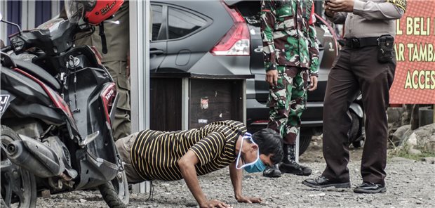 Die härtesten Corona-Strafen der Welt Indonesien, Makassar: Ein Motorradfahrer wird infolge der Missachtung von Corona-Schutzmaßnahmen von Polizeibeamten mit dem öffentlichen Vorführen von Push-Ups bestraft.