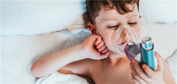 Ein kleiner Junge liegt auf dem Bett und inhaliert.