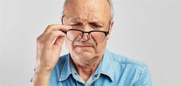 ein älterer Mann nimmt seine Brille ab und kneift die Augen zusammen.