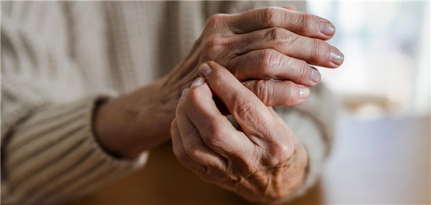Eine ältere Frau mit rheumatoider Arthritis reibt sich die schmerzenden Hände.