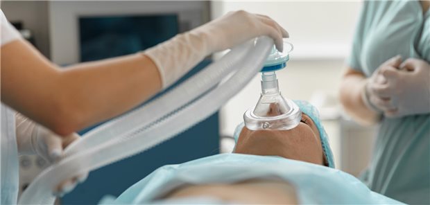 Nahaufnahme der Hände einer Anästhesistin, die eine Atemmaske über das Gesicht einer Patientin hält, um eine Vollnarkose einzuleiten.