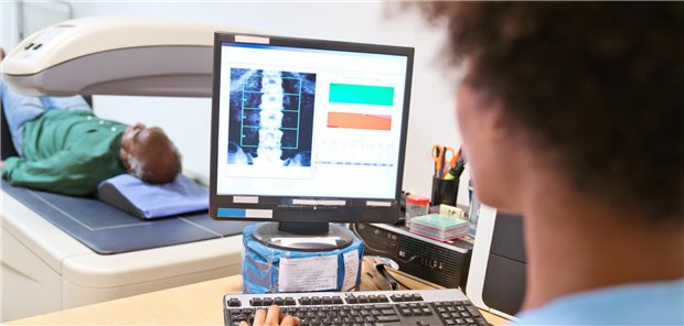 Eine Krankenpfleger analysiert das gerade aufgenommene Röntgenbild eines älteren Patienten auf einem Computermonitor.