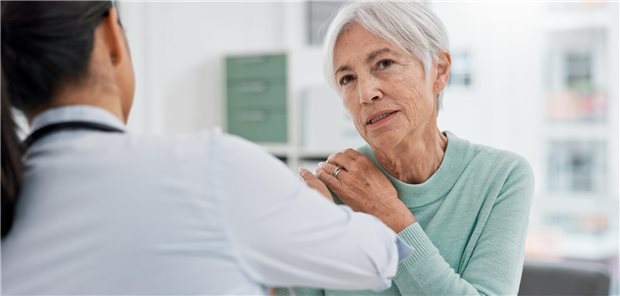 Ältere Patientin in der Arzt-Praxis beschreibt Schmerzen in der Schulter.