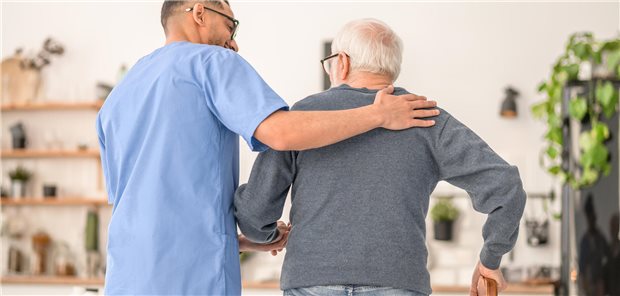 Pfleger hilft Patienten beim Gehen.