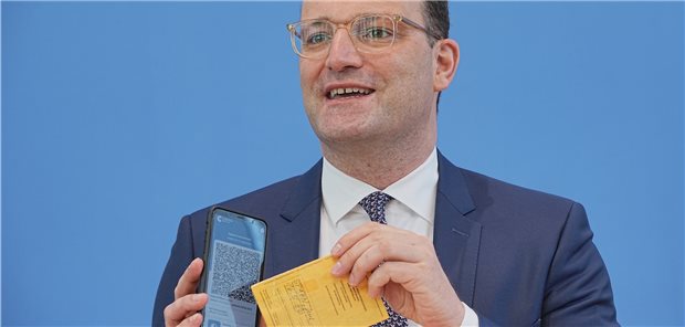 Jens Spahn (CDU) zeigt die Corona-Warn-App mit einem Muster eines digitalen Impfzertifikats sowie seinen eigenen alten Impfpass. Auch wenn der digitale Impfnachweis bis Ende Juni allen zur Verfügung stehen soll, hat das gelbe Heft noch nicht ausgedient.
