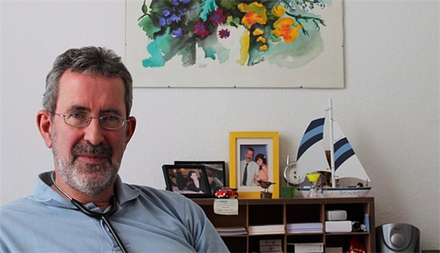 Selbst sonntags können Patienten kommen Jörg Krause in einem seiner Sprechzimmer. Das Sommeridyll hinter ihm hat seine Frau gemalt.