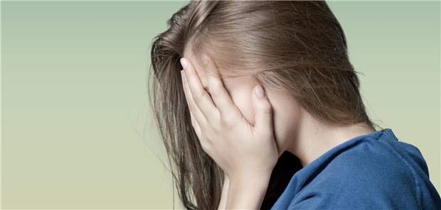 Ein junges Mädchen schlägt die Hände vors Gesicht.