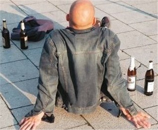 Weg in Alkoholismus beginnt bei Geburt Junger Mann umgeben von Bierflaschen. Ein schwieriges Umfeld in der Kindheit ebnet den Weg für Alkoholmissbrauch.