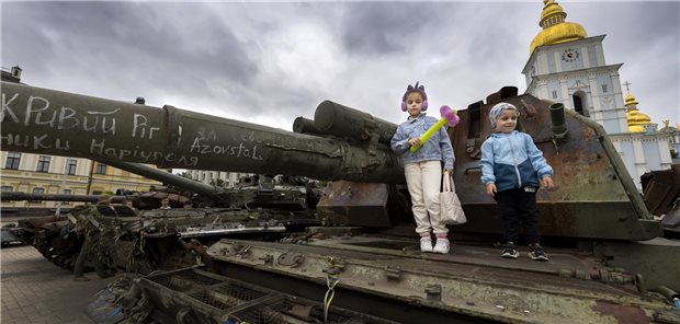 Kinder stehen auf einem ausgebrannten russischen Panzer auf dem St. Michaels-Platz in Kiew. Bilder und Berichte vom Angriffskrieg Russlands bedeuten für viele Menschen Stress.
