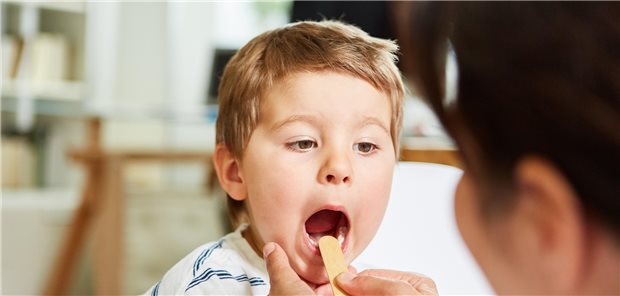 Kinderarzt mit Spatel untersucht Kind mit Mandelentzündung: Pädiater in Berlin fordern, mehr Sitze zu schaffen.