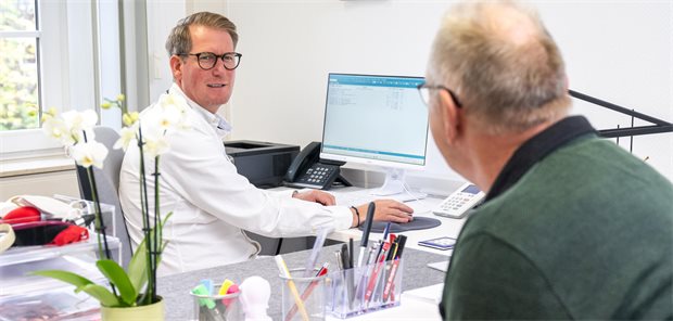 Das Bild zeigt eine Gesprächssituation zwischen Hausarzt und Patient in der Praxis.