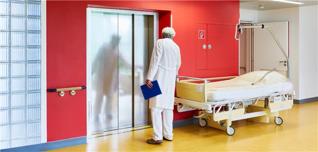 Arzt mit Bett vor einem Aufzug.