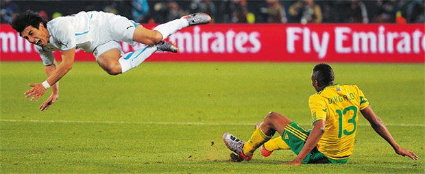 Späher, Spickzettel und flatterhafte Flugobjekte Kommt ein Spieler geflogen: Jorge Fucile (l.) aus Uruguay, in der Luft, Kagisho Dikgacoi (r.), Südafrika, am Boden