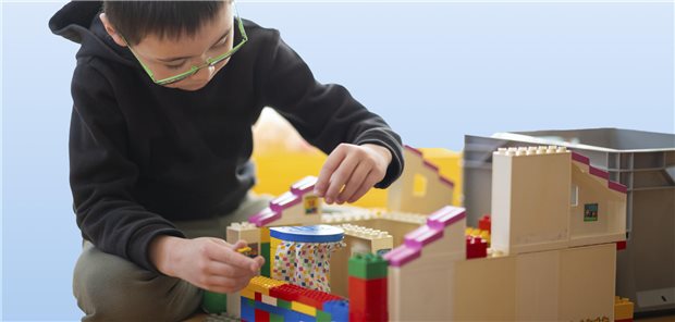 Ein Junge baut ein Haus aus Lego.