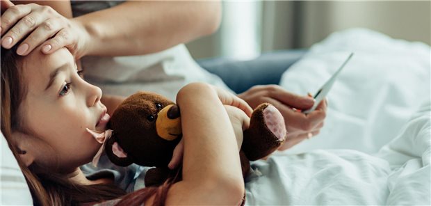 Kind im Bett wird Fieber gemessen.