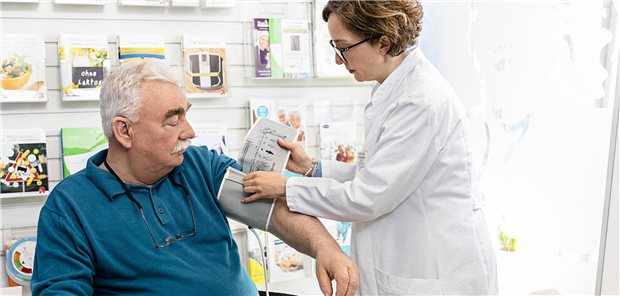 eine Apothekerinn misst Blutdruck bei einem älteren Mann