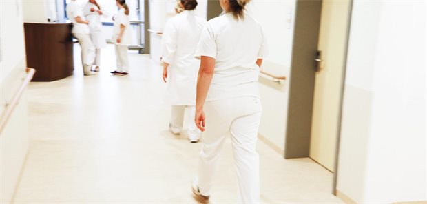 Pflegekräfte und Ärztinnen laufen über einen Gang eines Krankenhauses.