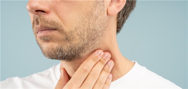 Nahaufnahme wie ein Mann seinen Hals aufgrund einer Sekretakkumulation im Rachenbereich (postnasaler Drip) bei einer chronischen Rhinosinusitis.