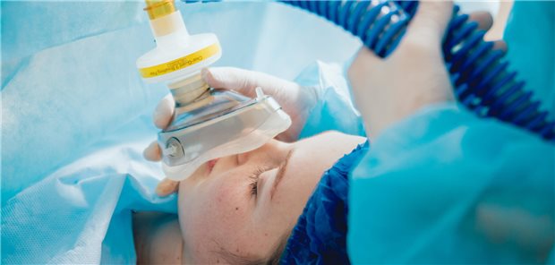 Ein Anästhesist führt die Pre-Oxygenierung für die Vollnarkose bei einer Patientin durch.