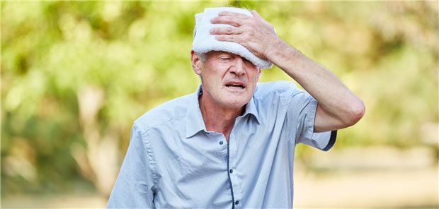 Älterer Herr hält sich ein feuchtes Handtuch an die Stirn.