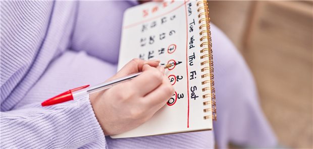 Frau streicht Daten in Kalender.