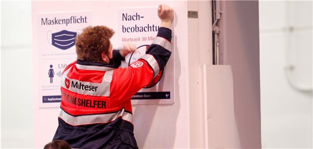 Corona-Impfstart wohl nicht vor Januar 2021 Malteser Rettungshelfer befestigen in einem Impfzentrum in Essen Hinweisschilder an den Wänden. In der Messehalle sollen, wenn der Impfstoff bereitsteht, bis zu 2400 Menschen pro Tag geimpft werden.