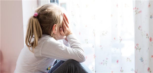 Ein kleines Mädchen sitzt während der Corona-Pandemie in ihrem Zimmer vor der Balkontür.
